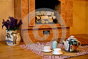 A fireplace with firewood in a rustic cottage, a carpet with cus