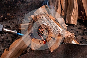 Fireplace kindling of chopped wood logs by gas torch. Method of firing at camping outdoor. Close up image of burning woods and