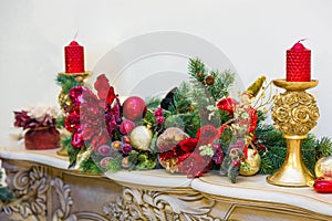 A fireplace mantle is decorated for Christmas with garland, lights, a bow and other decorations
