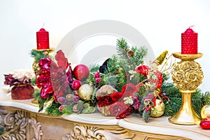 A fireplace mantle is decorated for Christmas with garland, lights, a bow and other decorations