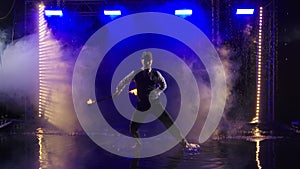 Fireshow performance with burning torch performed by a man in a suit and hat. Fire show in the rain in the studio. Slow