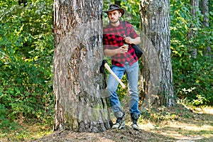 Firewood as a renewable energy source. Lumberjack with axe on forest background. Deforestation is a major cause of land