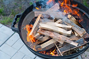 Firewood is being burn in the barbecue grill. smoke is spreading through the air. Grill for frying steaks in the backyard of the