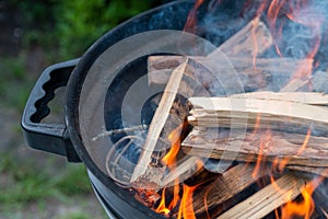 Firewood is being burn in the barbecue grill. smoke is spreading through the air. Grill for frying steaks in the backyard of the