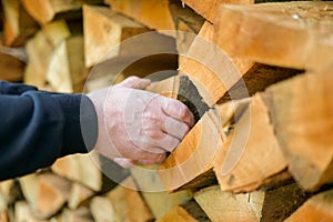 Firewood close-up. solid fuel.Male hands pulling a log from a woodshed. Heating season.Heating season.Prices for