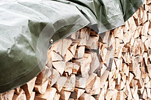 Firewood covered with a waterproof green tarpaulin