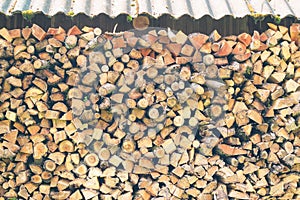 Firewood or fuelwood stacked by a wall. Texture woodpile