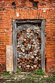 Firewood lies in the doorway, red brick wall