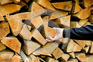 Firewood and mens hands.solid fuel.Male hands pulling a log from a woodshed. Heating season.Prices for firewood and