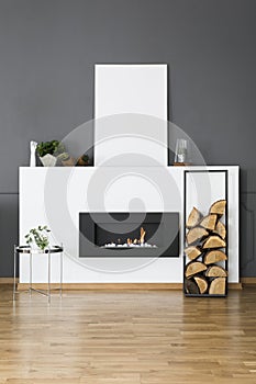 Firewood and silver table in front of fireplace in loft interior