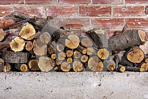 Firewood stacked on concrete and a brick wall photo