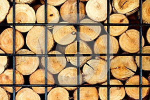 Firewood stacked on the woodpile in iron cage, background.