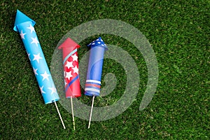 Firework rockets on green grass, flat lay. Space for text