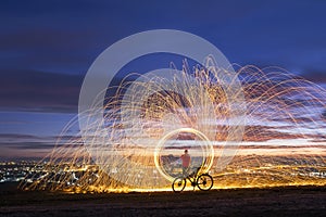 Firework showers of hot glowing sparks from spinning steel wool in night city.