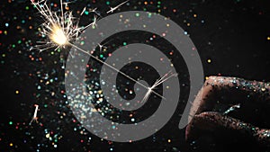 Firework sparkler on festive glittering backdrop