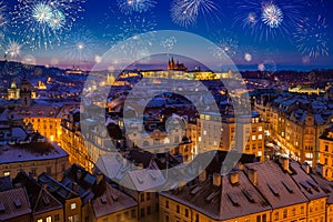 Fireworks above Prague Castle with snowy rooftops during late christmas sunset