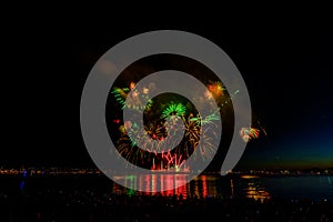 Fireworks over the ocean in the big city, silhouettes of people