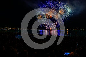 Fireworks over the ocean in the big city, silhouettes of people