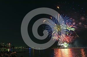 Fireworks over the ocean in the big city, silhouettes of people