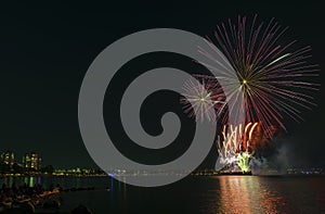 Fireworks over the ocean in the big city, silhouettes of people