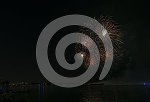 Fireworks over the ocean in the big city, silhouettes of people