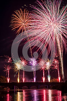 The fireworks on stoned bridge on the Orb River with reflection in Beziers in France