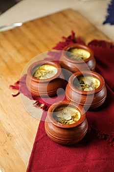 Firni, phirni anf kheer with nuts served in pot isolated on mat top view of indian, bangali and pakistani dessert mithai