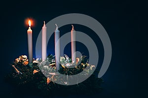 First advent candles burning on black background