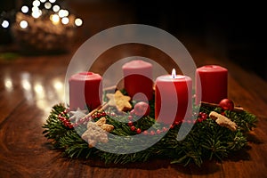 First Advent - decorated Advent wreath from fir branches with red burning candles on a wooden table in the time before Christmas,