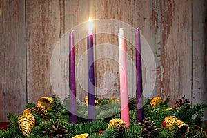 First advent with three burning candles on fir branches with Christmas decoration