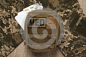 First aid kit and military uniform on wooden table, flat lay