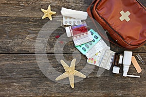 First aid kit on old wooden background. Concept of medication required in journey.