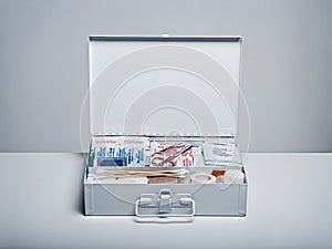 First aid kit packed with medical supplies on grey background photo