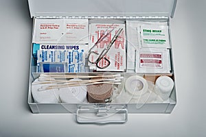 First aid kit packed with medical supplies on grey background photo