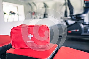 First aid kit red box in the fitness gym opposite the sport equipment and jogging simulators. Healthy lifestyle, safety and help.