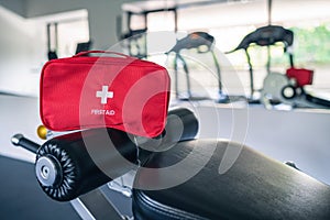 First aid kit red box in the fitness gym opposite the sport equipment and jogging simulators. Healthy lifestyle, safety and help