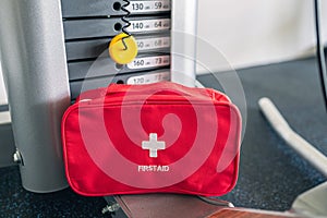 First aid kit red box in the fitness gym opposite the sport equipment and jogging simulators. Healthy lifestyle, safety and help