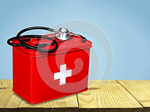 First aid kit with stethoscope on wooden table