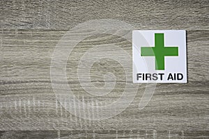 First aid sign on the wooden wall with space for adding text on the left side