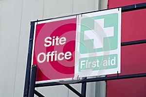 First aid site office sign on construction building door railing for workplace health and safety green cross