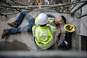 First aid support accident at work of construction worker at site. Builder accident falls scaffolding on floor, Safety team helps