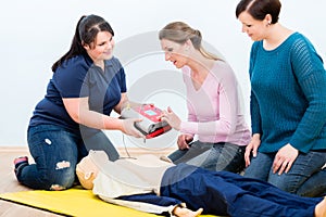 First aid trainees learning to use defibrillator for reanimation