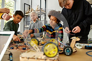 First Attempts In Learning. Diligent girl and boys making a vehicle at a technology class. Smart kids and STEM education