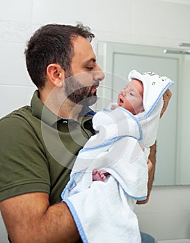 First bath of newborn baby boy. The baby is in the bathrobe in his father`s arms