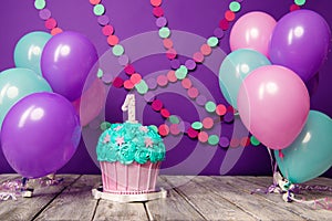 First birthday cake with a unit on a purple background with balls and paper garland.