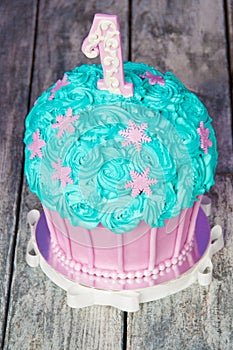 First birthday cake with a unit on a purple background with balls and paper garland.