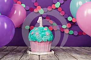 First birthday cake with a unit on a purple background with balls and paper garland.