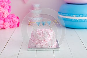 First birthday smash the cake. A pink cake stands on a white wooden background. First birthday.