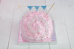 First birthday smash the cake. A pink cake stands on a white wooden background. First birthday.