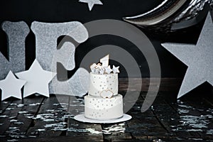 First birthday white cake with stars and candle for little baby boy and decorations for cake smash. Big silver letters ONE, silver